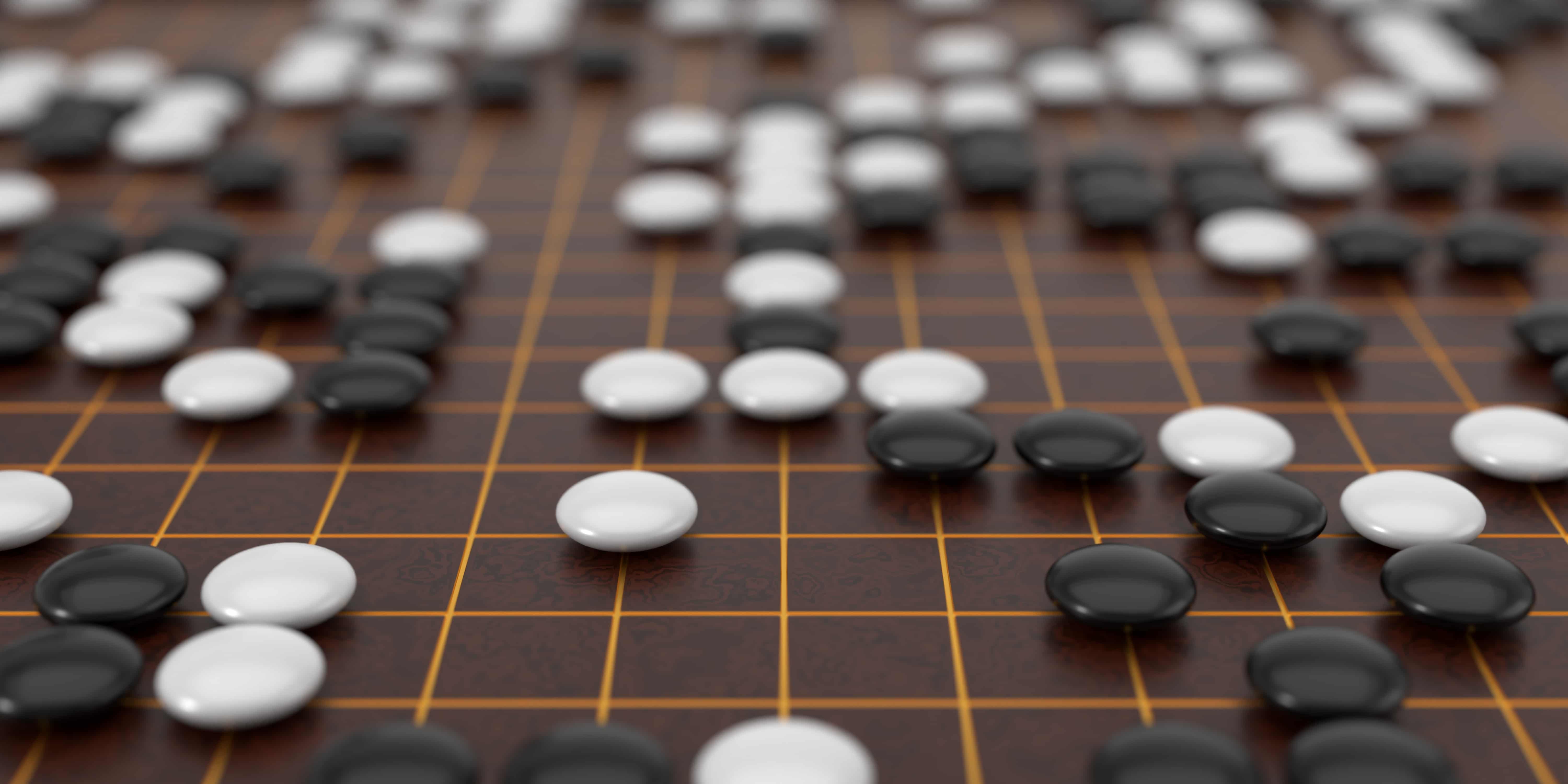 A close-up of a Go board with black and white stones placed on a wooden grid. The board shows a complex game state with strategic patterns emerging.